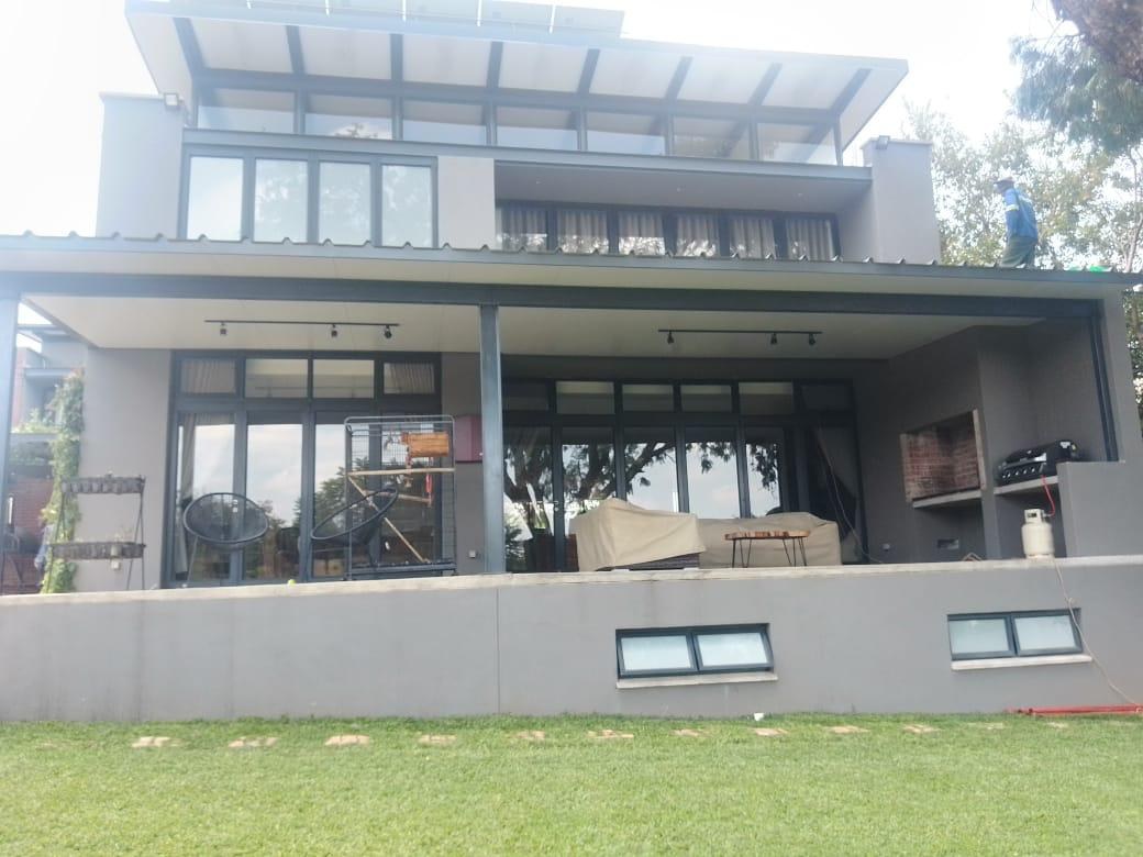 Completed IBR roof and flat-panel patio canopy on a residential installation, roof sheeting visible along the ridge