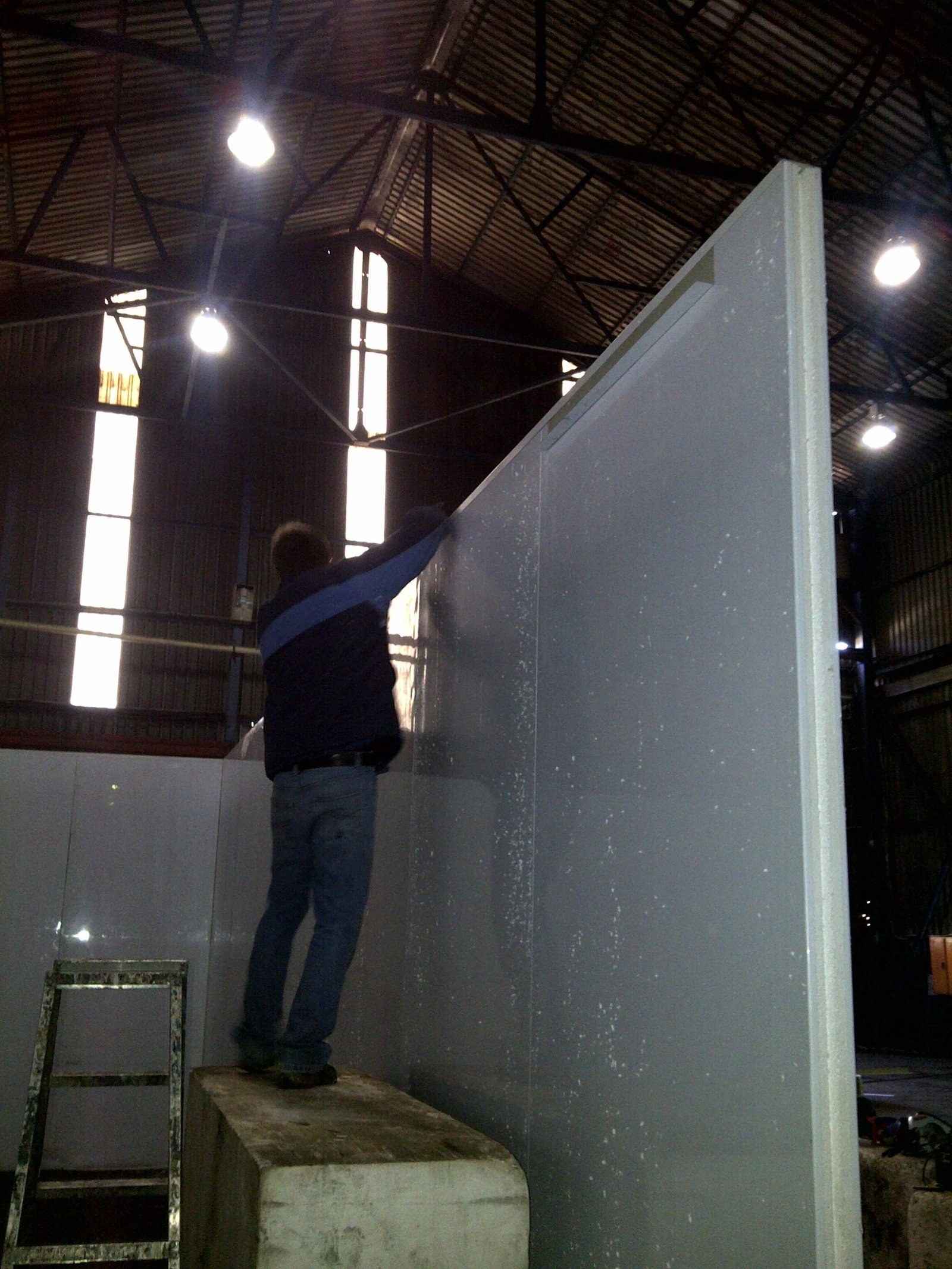 Insulated wall panel joint being taped during installation, foam core and panel edge visible at the seam