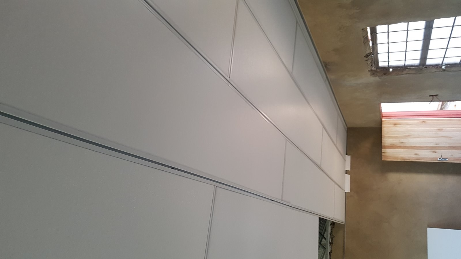 Wall and ceiling panel join at a roof skylight opening, building still under construction