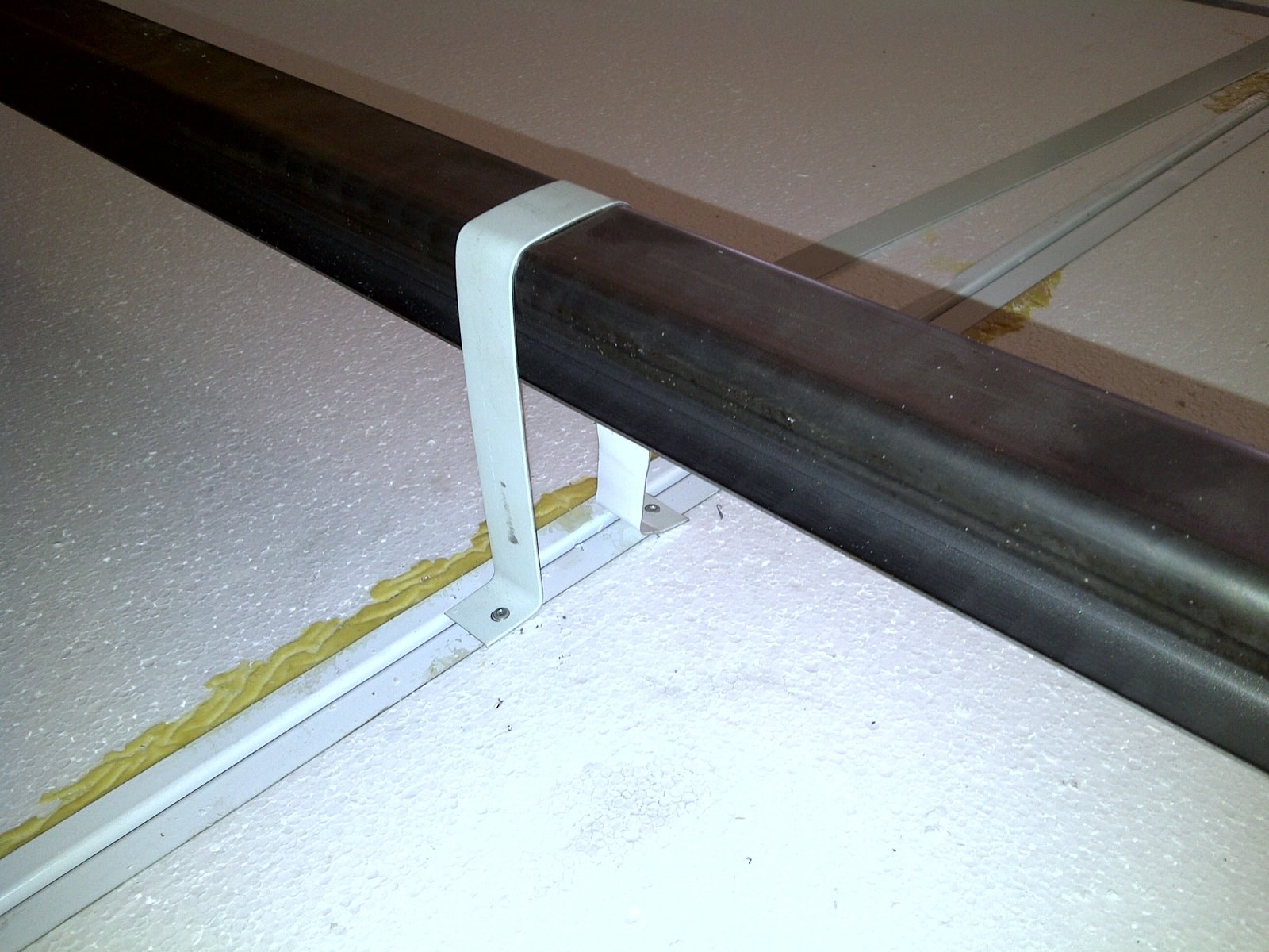 Close-up of a clip bracket securing a ridge bar over an insulated panel seam