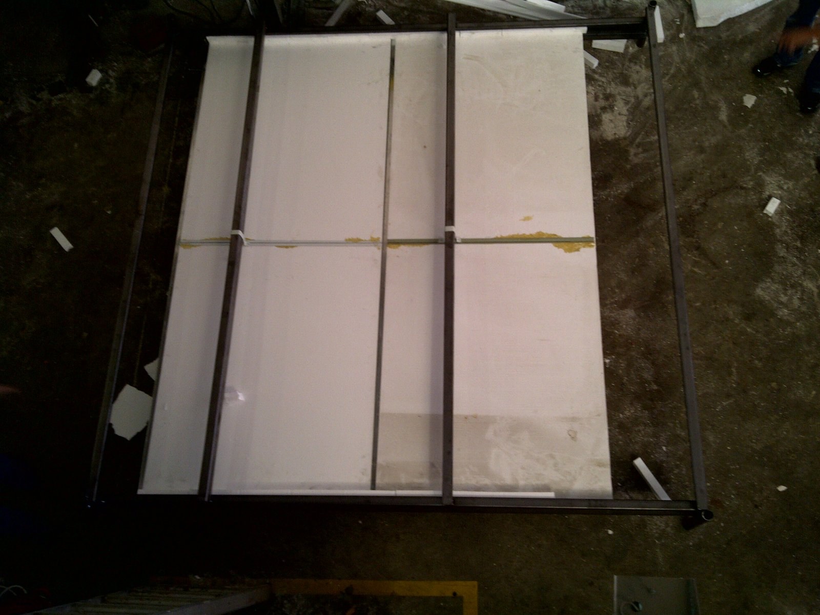 Top-down view of a steel panel frame with EPS core boards assembled inside, workshop floor