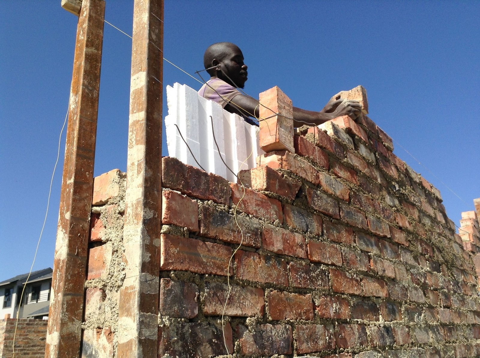 Mason laying brick over an EPS cavity board, house under construction