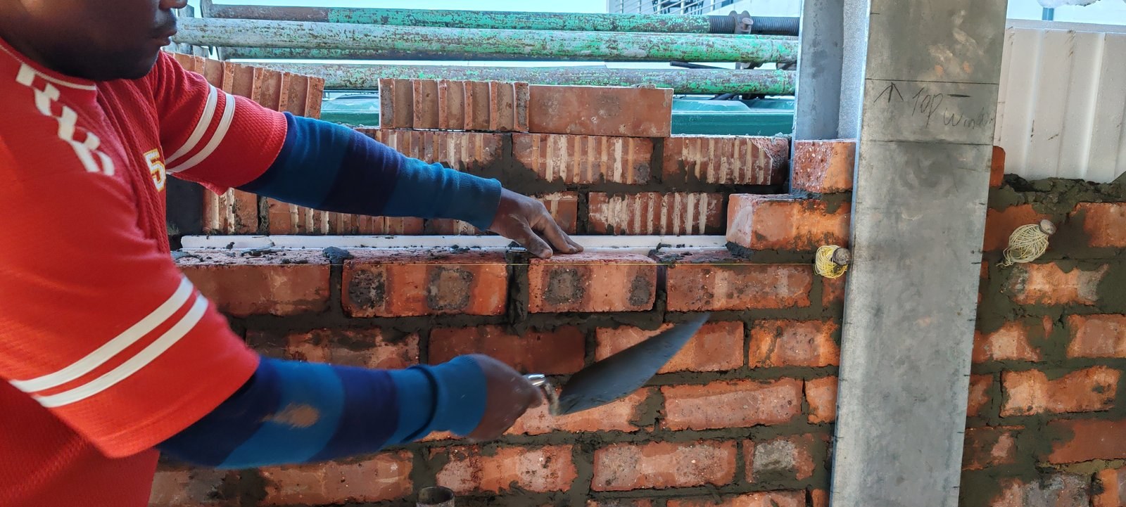 Bricklayer pointing mortar over a cavity board above a window lintel