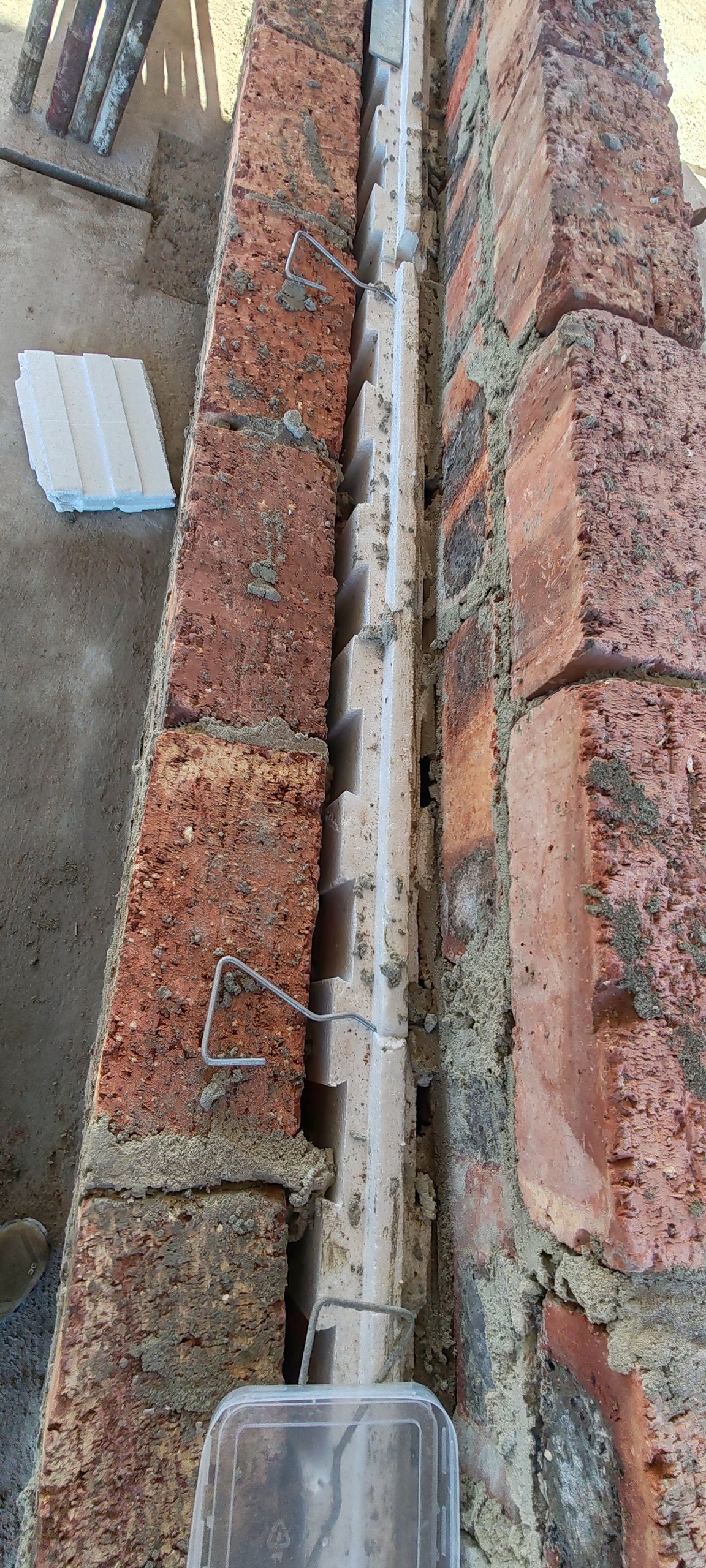 Interlocking cavity board edge fitted between two brick leaves, closeup