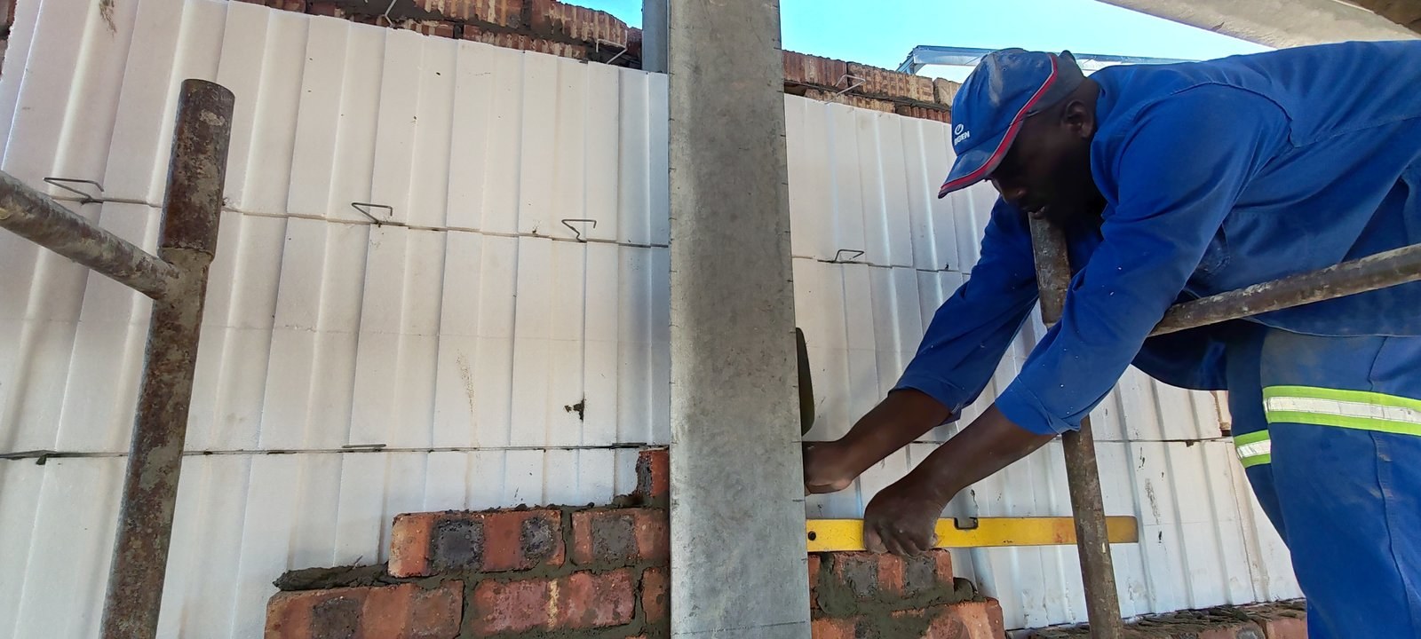 Checking brick level against a cavity board wall, high-rise buildings in background