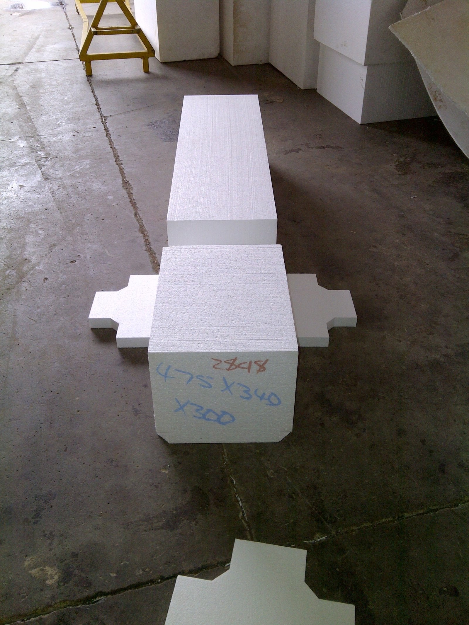 Custom-cut void former pieces with dimensions marked in pen, laid out on the workshop floor