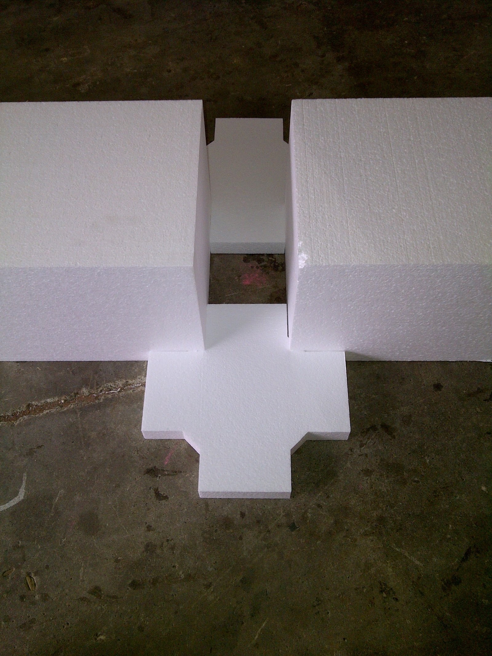 Cross-shaped void former pieces positioned end to end, showing the void gap they leave between beams