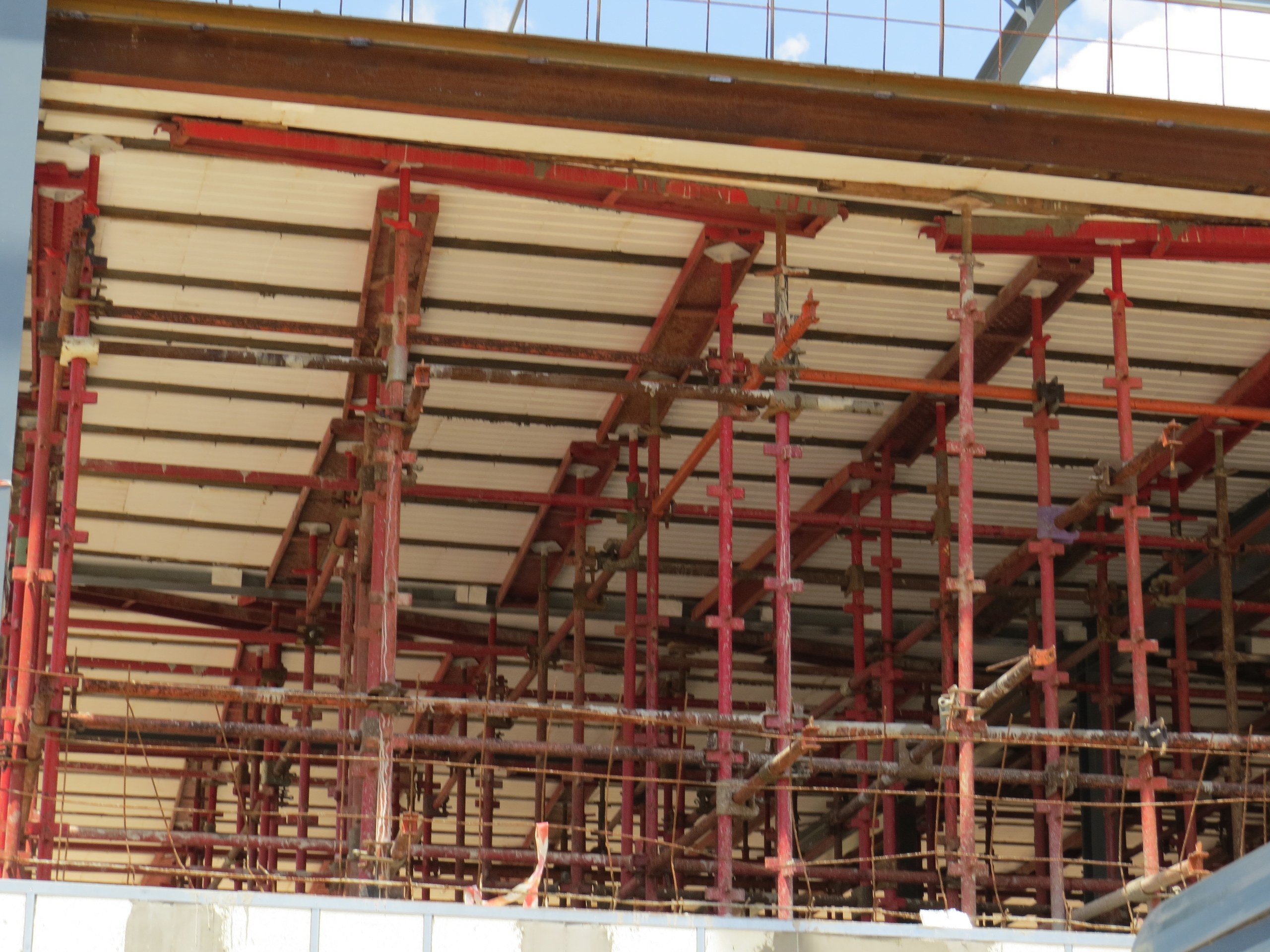 The underside of a suspended floor slab during construction: white moulded EPS void formers span between the joists, held up on a dense array of props while the concrete topping over them cures. The blocks are what make the slab a rib-and-block floor rather than a solid one.