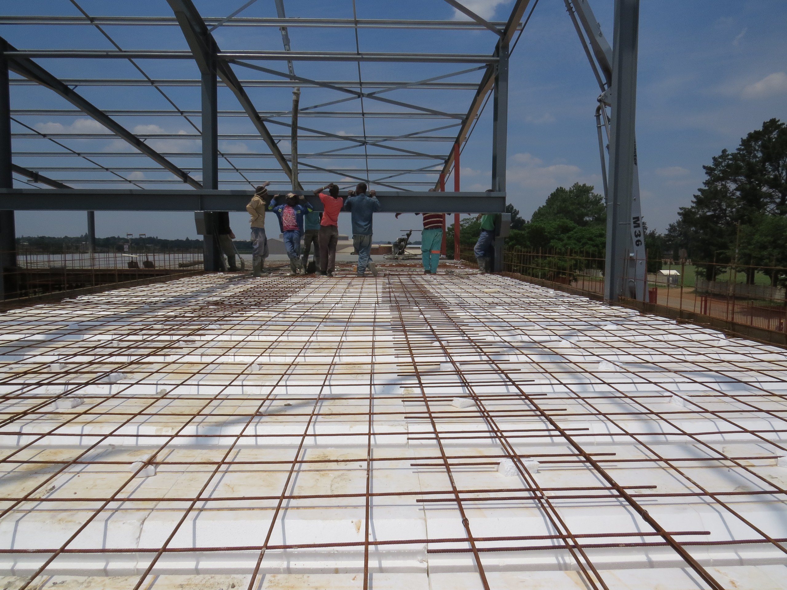 Looking down the length of the slab: rows of void formers with the reinforcing mesh laid over them, ready for concrete. The lightweight blocks are quick to place by hand, with no shutter to the underside of each void.
