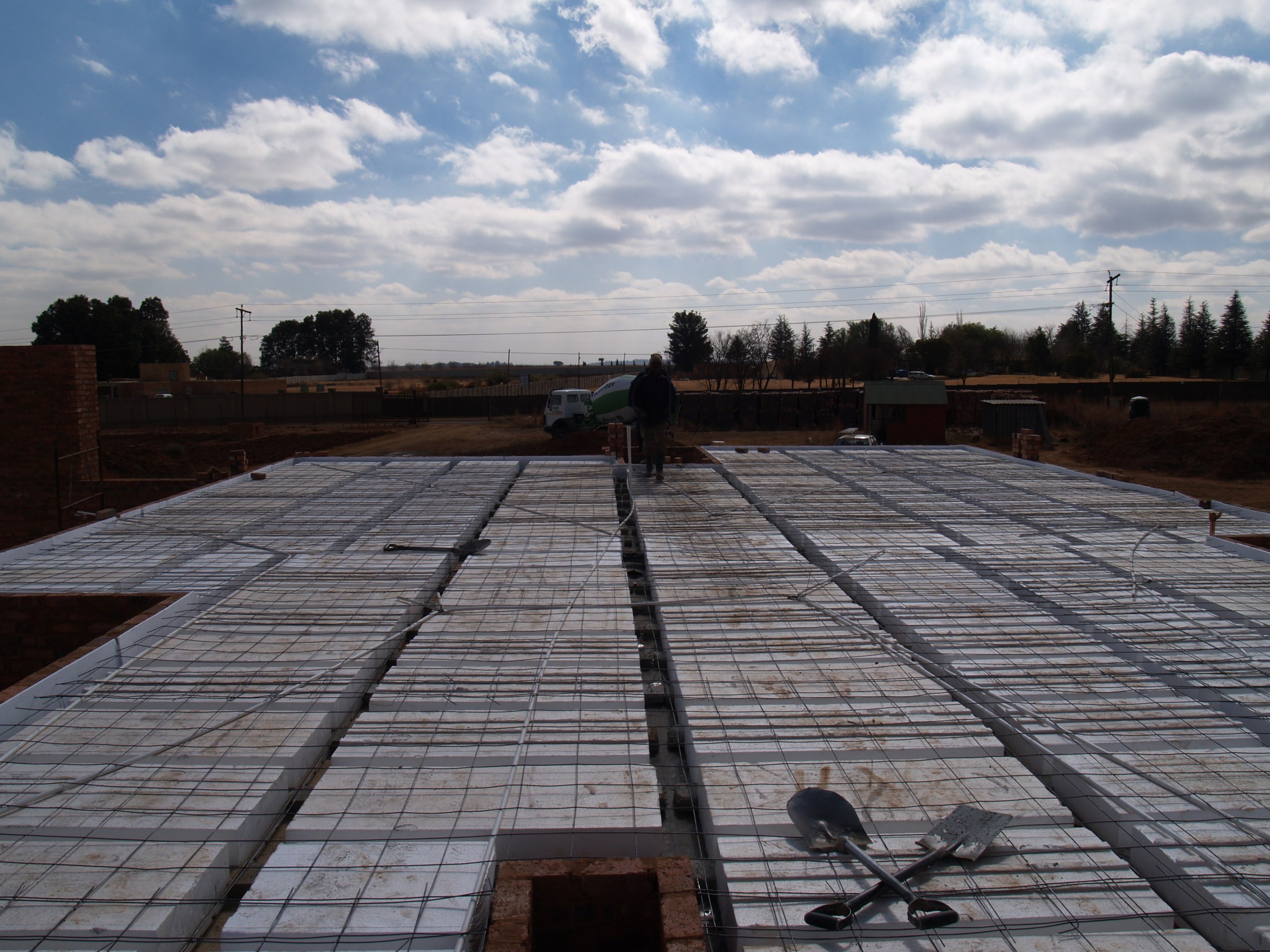 Void formers laid out across a whole floor with the reinforcing mesh over them, ready for concrete. The blocks tile the full area; only the ribs between them and a thin topping take concrete.