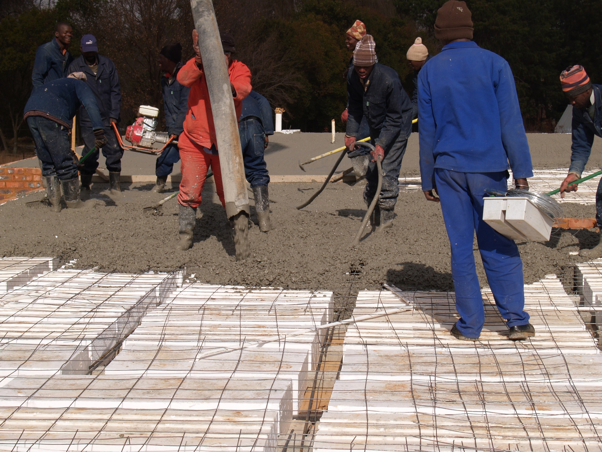 Placing and screeding the concrete over the void formers. The pour fills the ribs and the topping in one operation.
