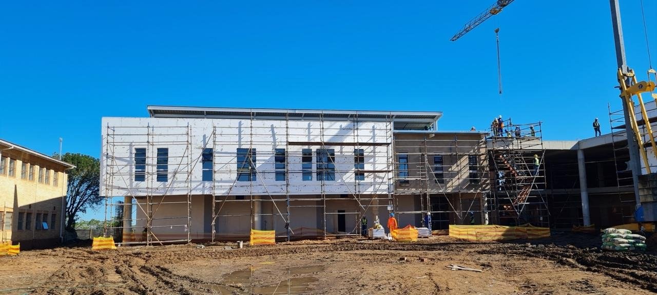 EPS boards fixed to a building facade ahead of basecoat and render, tower crane on site