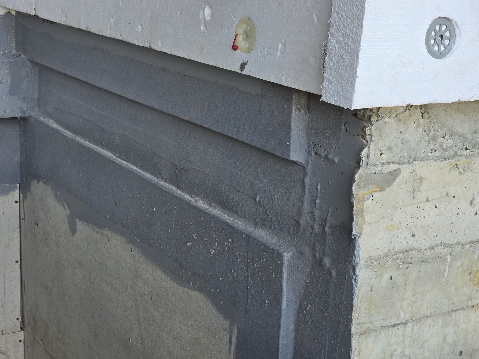 Mesh and basecoat detail at a window reveal corner, EPS board edge visible