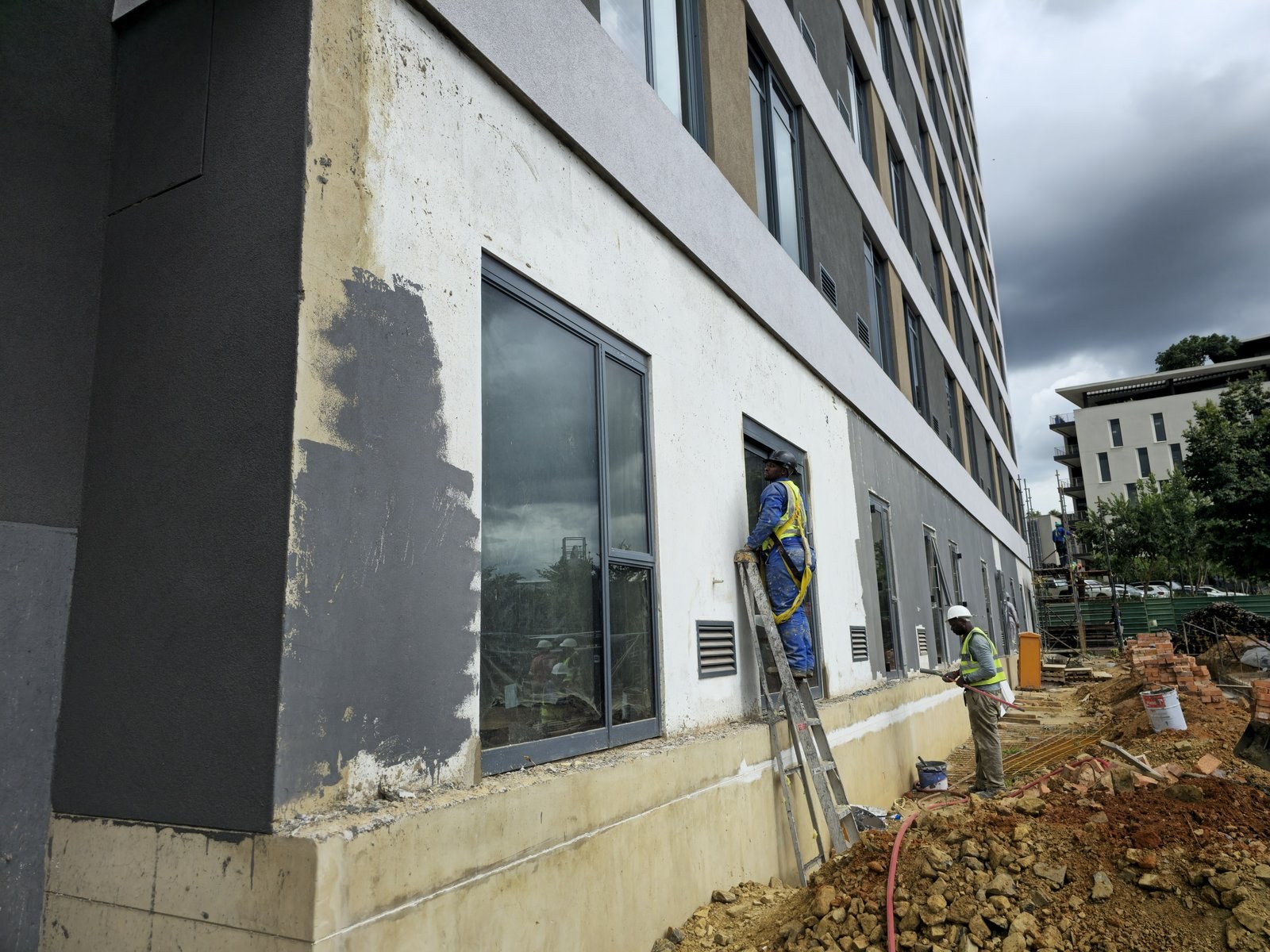 Workers applying and finishing render at ground floor level of a building under construction