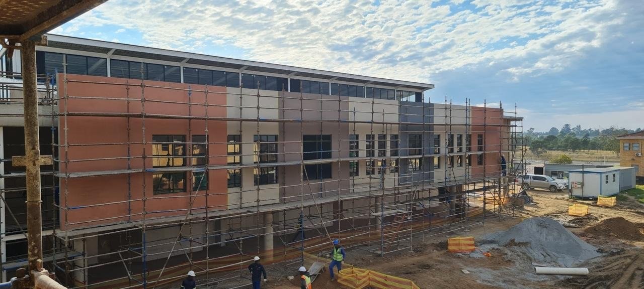 Colour-banded render facade still under scaffold, evening light