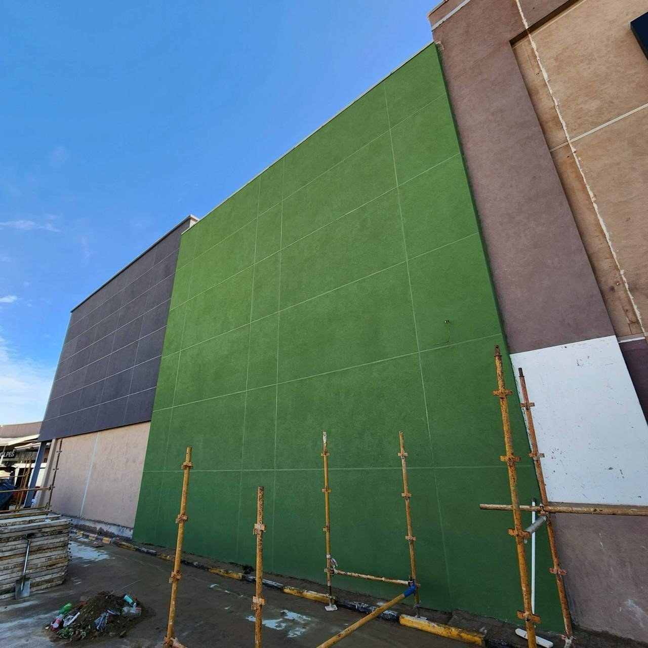 Completed render finish in a vivid green colour on a retail building wall